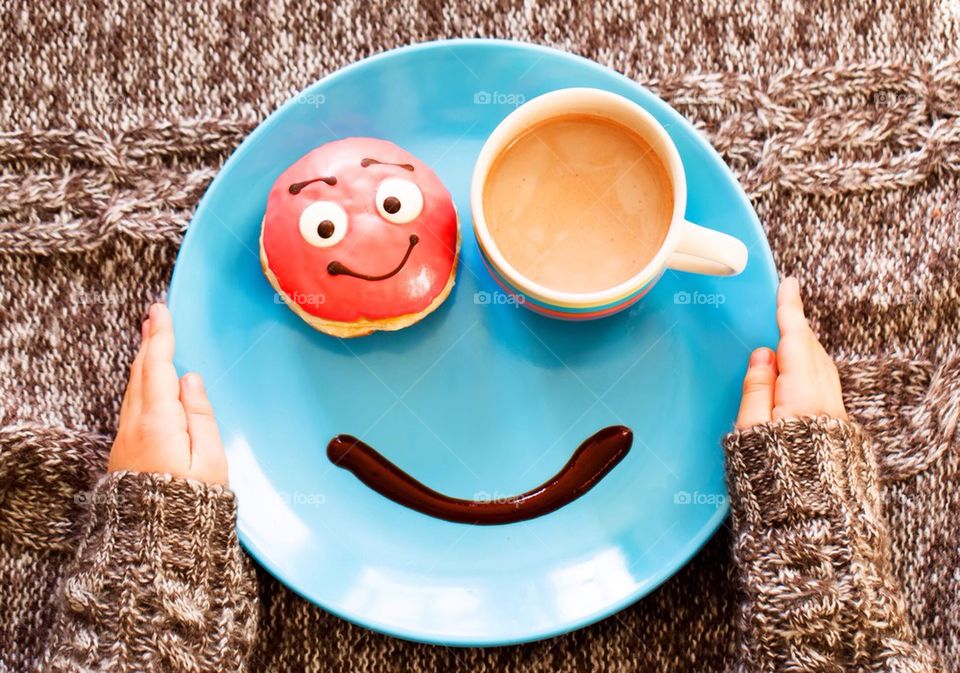 High angle view of girl's hand with doughnut and cup of tea