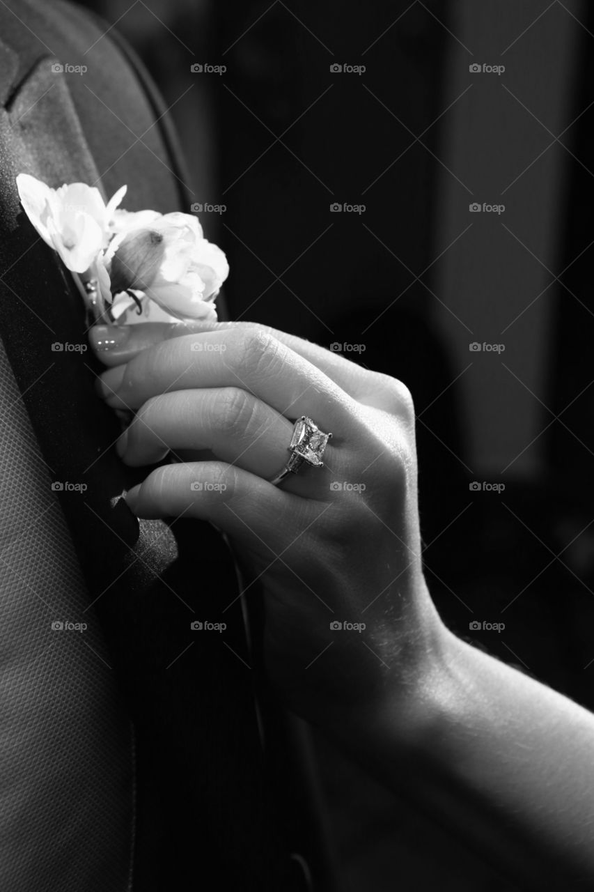 Woman hands fixing man's suit. Hands of woman affixing decorative boutonier om his suit. 