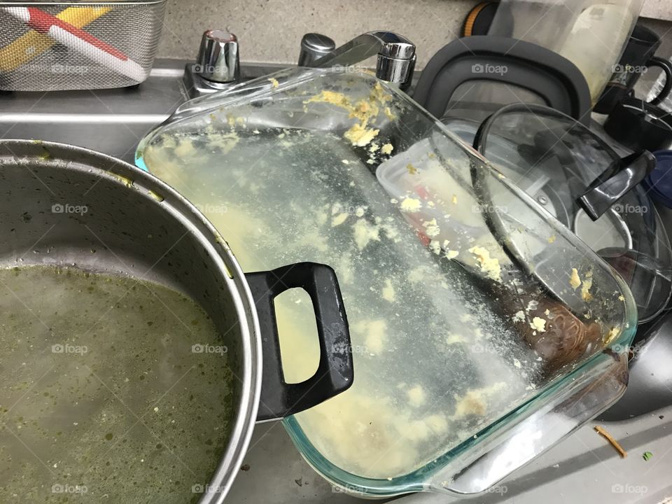 Dirty dishes piled up in a metal kitchen sink