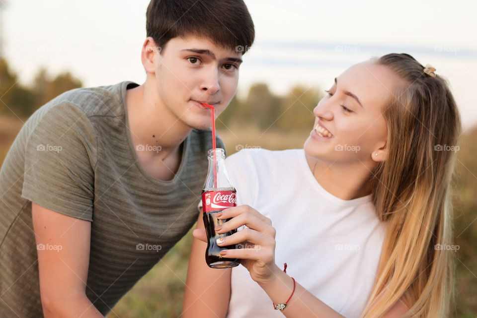 Girl looking at boy drinking cold drink