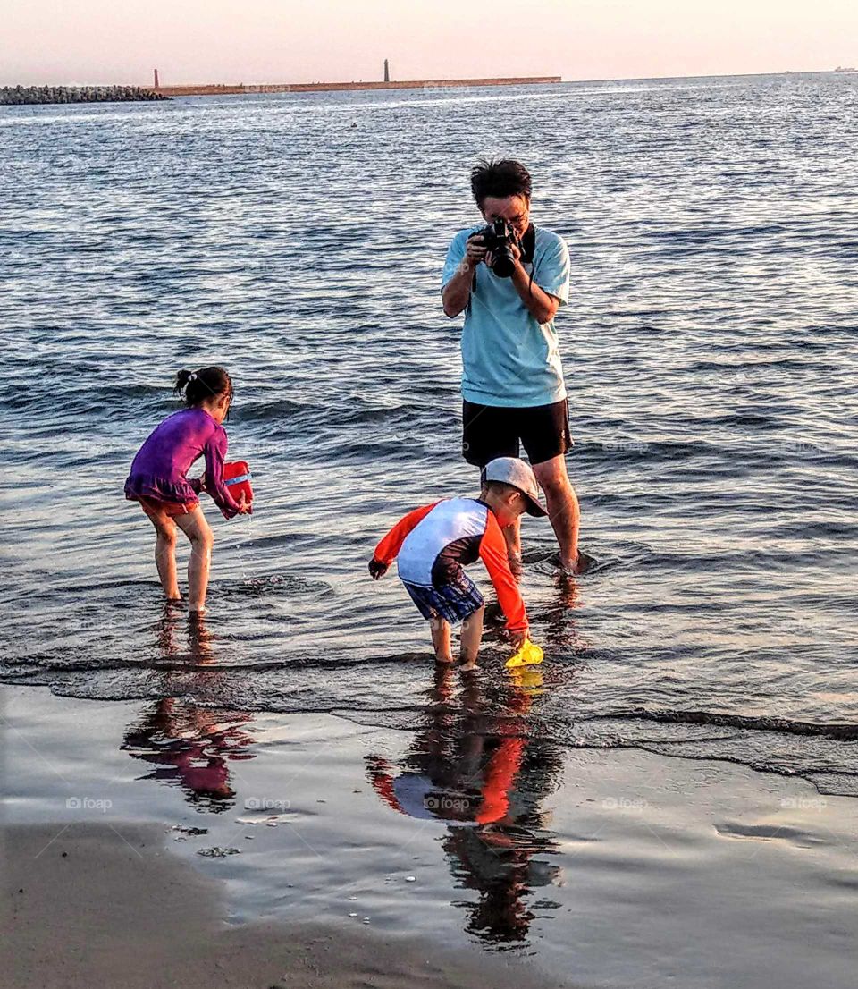The memories of summer: parents with children were going to the beach, playing happily, and then took some photos for their good childhood memories. a warm family life!