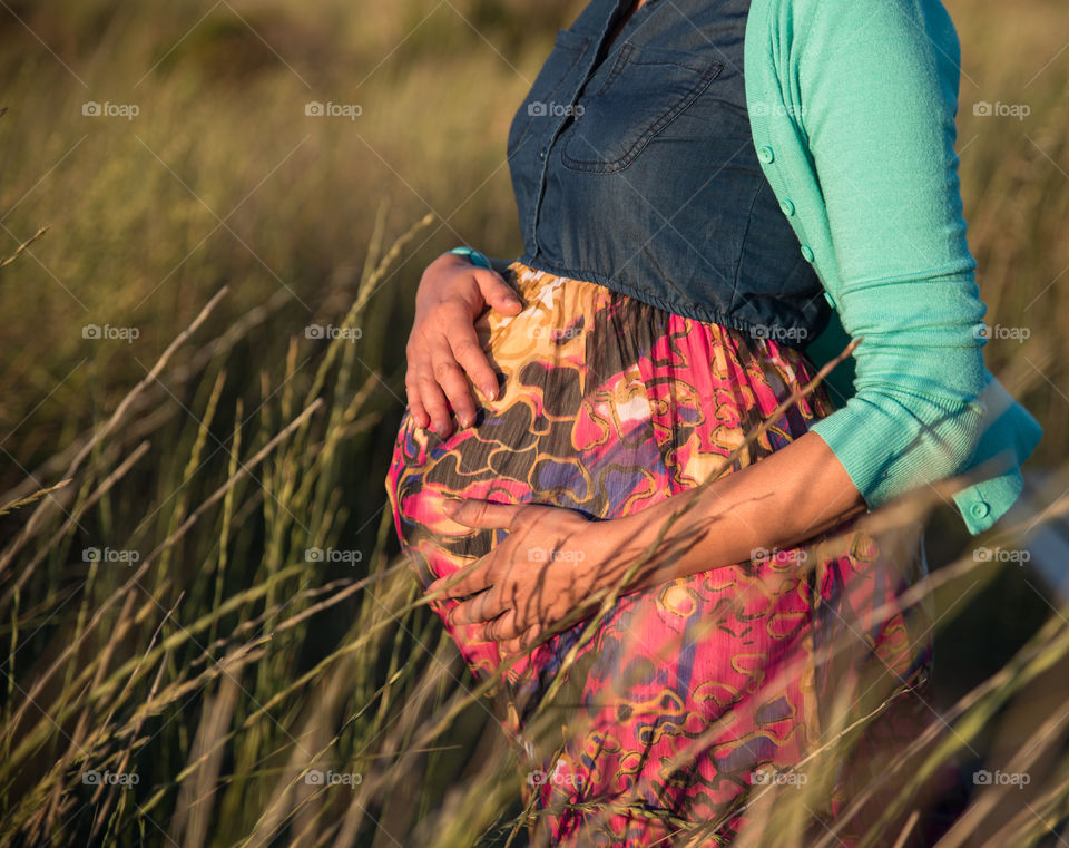 pregnant woman holds hands on belly