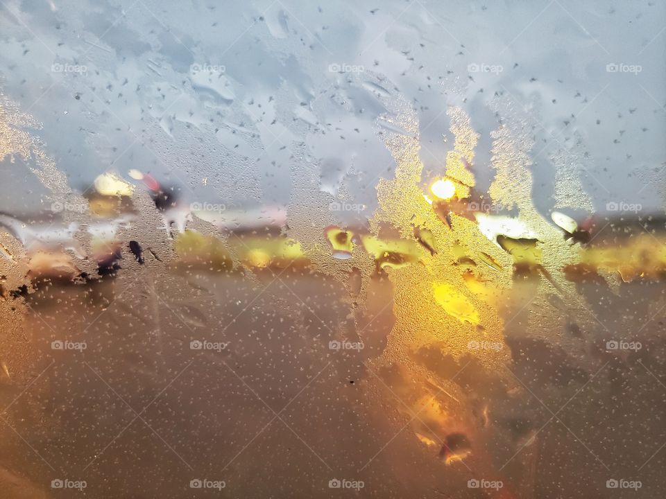View through a window with rain and cold winter condensation outside. Outside lighting gives the image an impressionistic art feel.