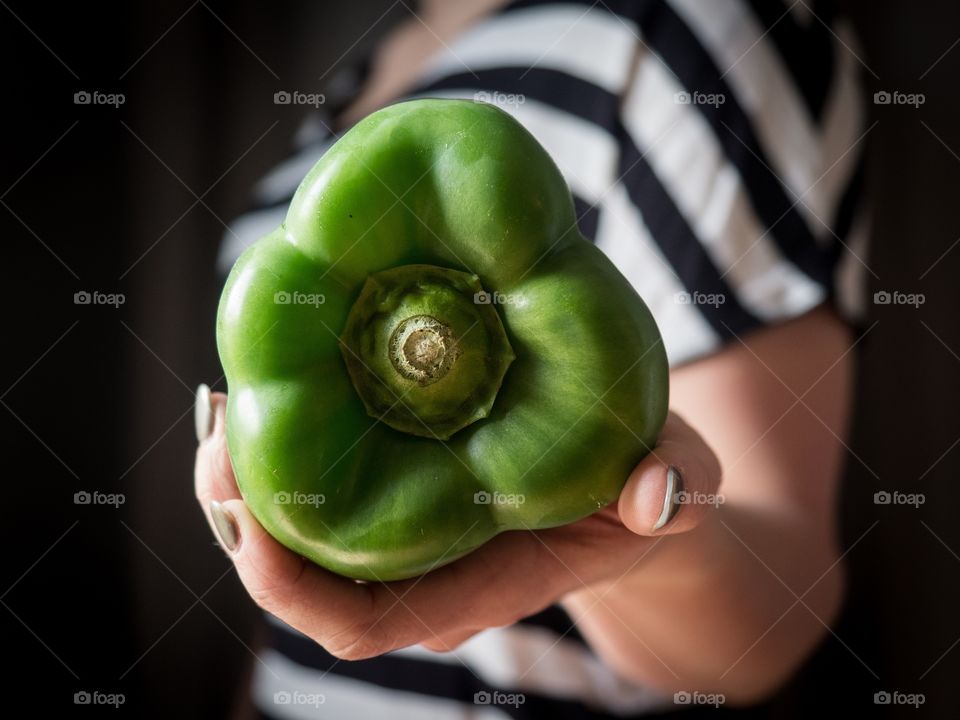 Mid section of girl holding a green bell pepper