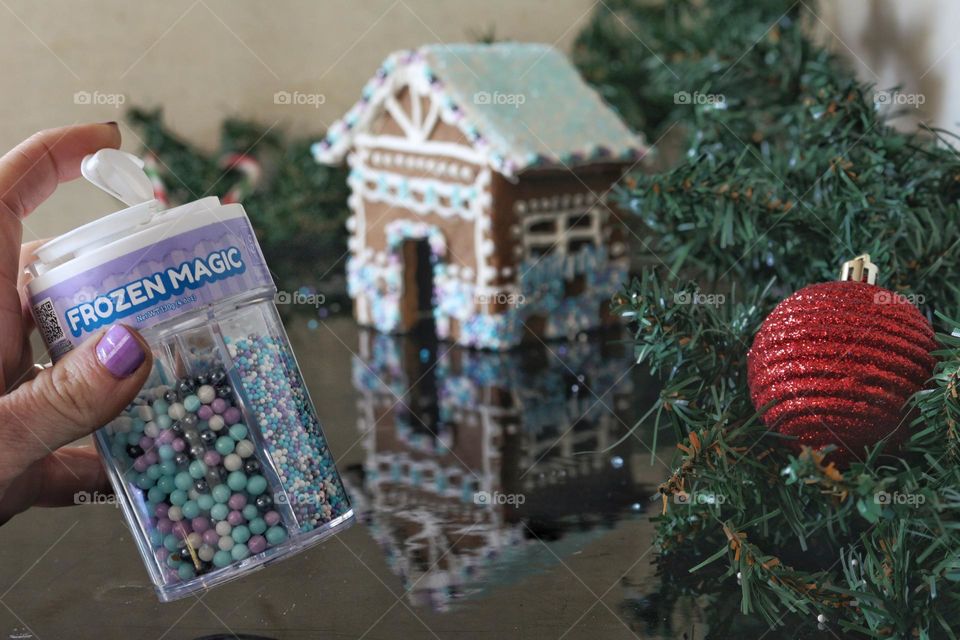 Decorating a homemade gingerbread house with Frozen Magic sprinkles by Twinkle baker decor.