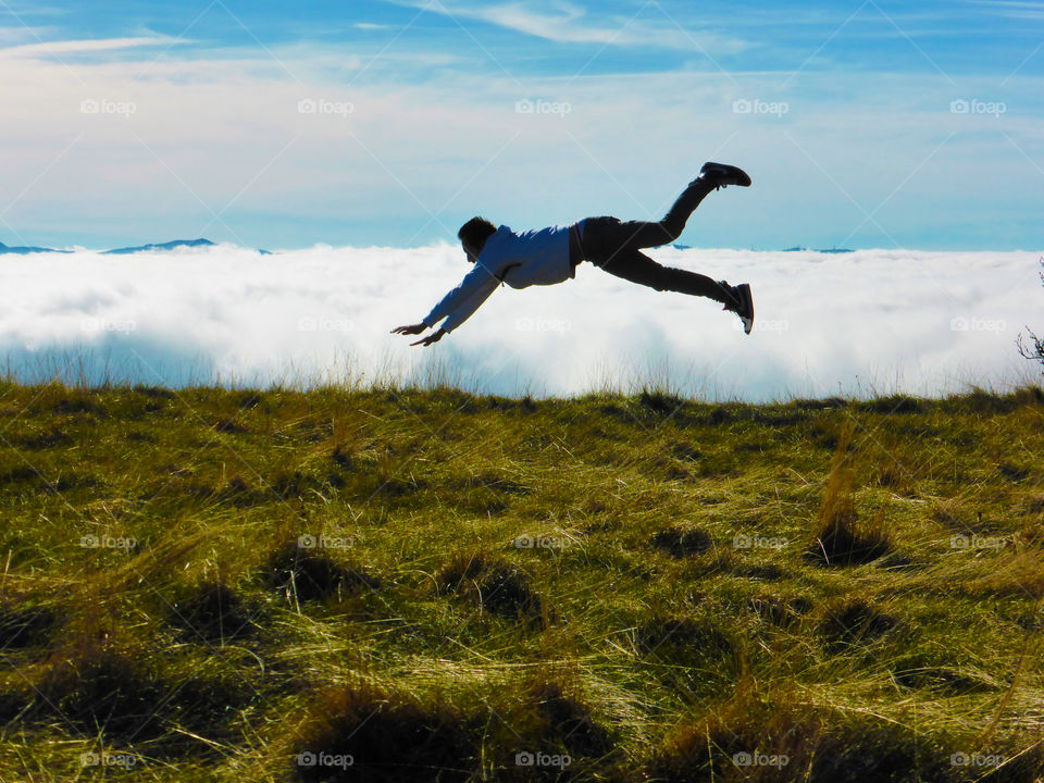 A man jumps between clouds and the ground