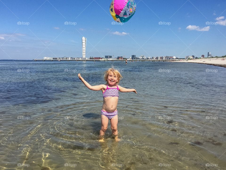 Little girl of three plays with a ball at Ribban beach in Malmö Sweden.