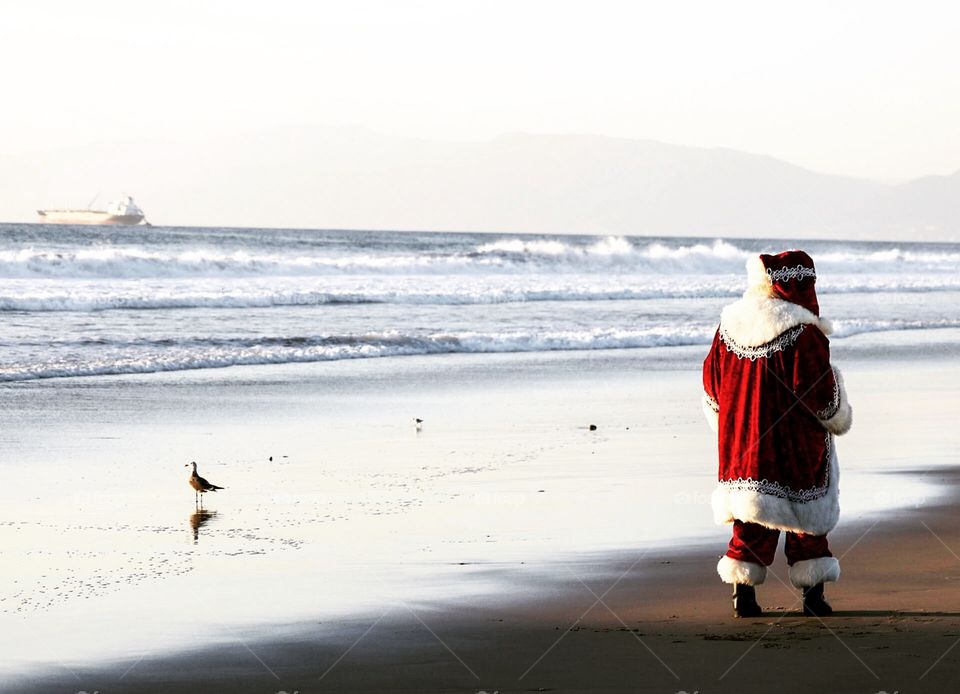 Santa walking the shoreline of Manhattan Beach, CA
