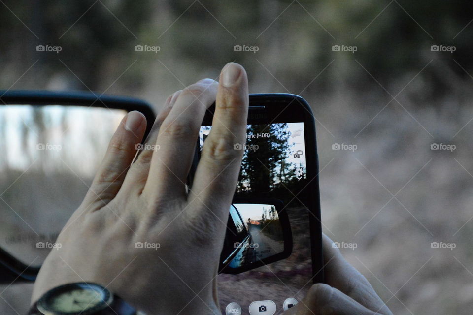 Photo of a photo. Mountains, trees, a mirror and two cameras