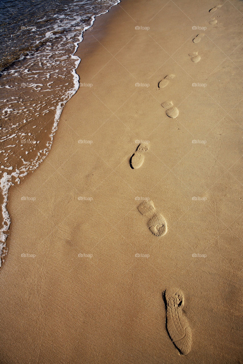 Shoe prints on sand at beach