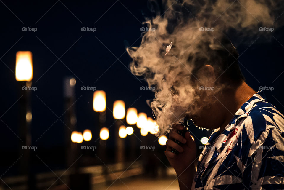 Dramatic smoking man on the side of the bridge at night