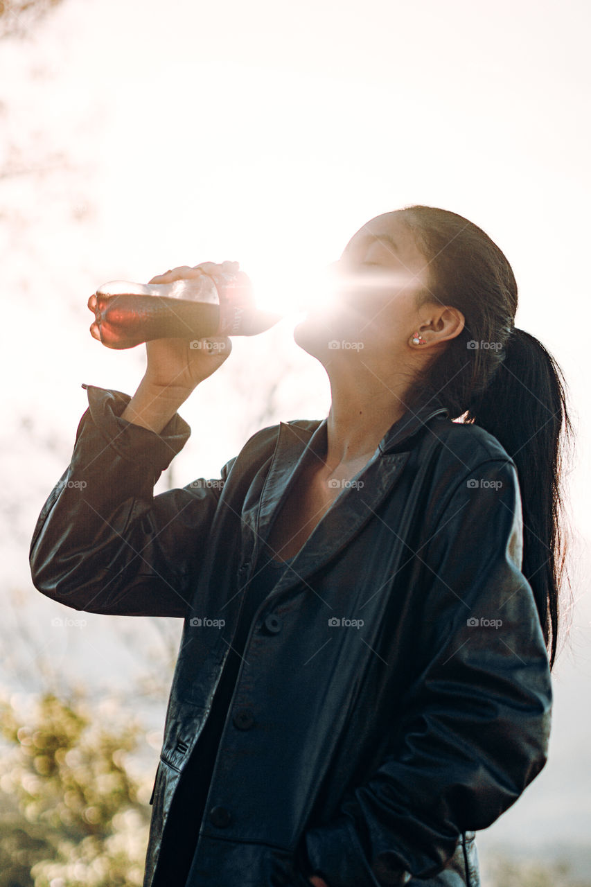 Girl enjoys a delicious Coca Cola in a hot sunrise in the middle of the mountain