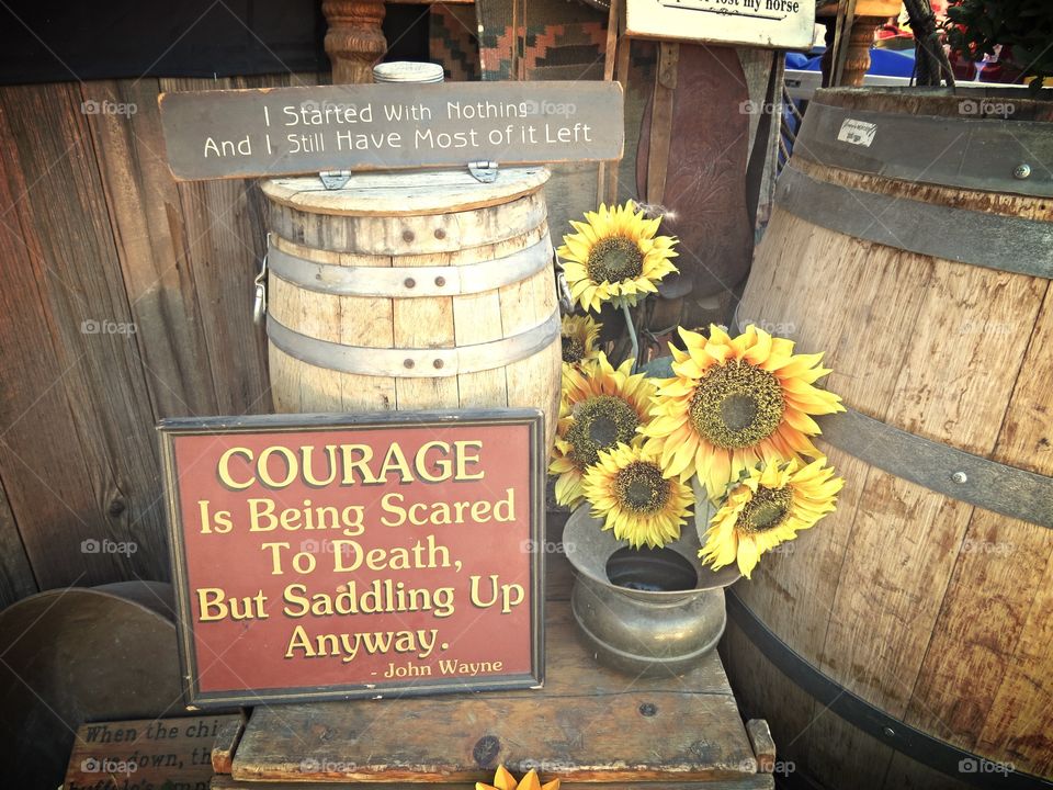 Vintage farm sign with barrels and sunflowers.
