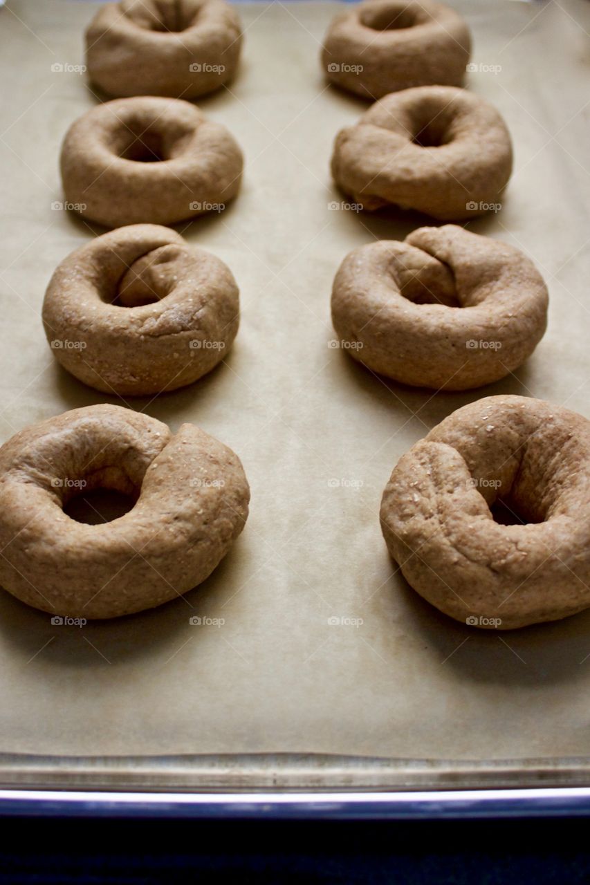 Angled view of sourdough spelt and wheat dough for bagels, on parchment paper on a stainless steel baking sheet