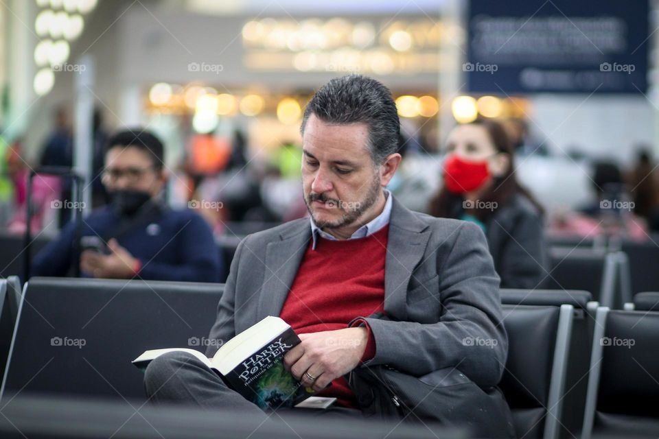 Man is reading Harry Potter book in the airport