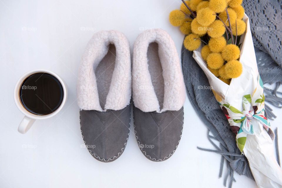 Grey and illuminating colors on a pair of slippers and bouquet of craspedia flowers 