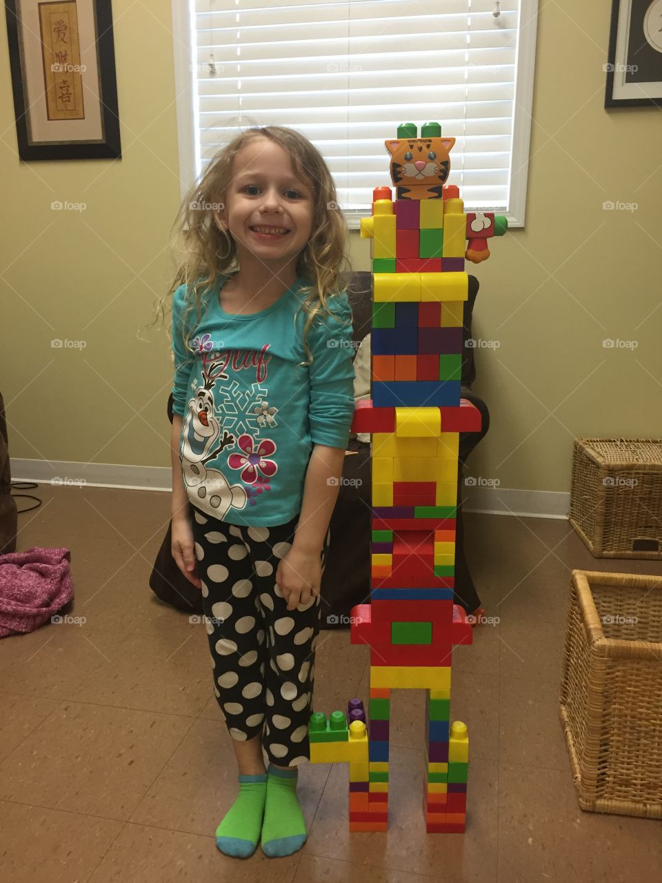 Happy little girl standing with stack of lego blocks