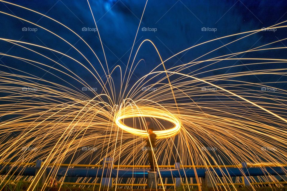 Man spinning steelwool against blue sky at night