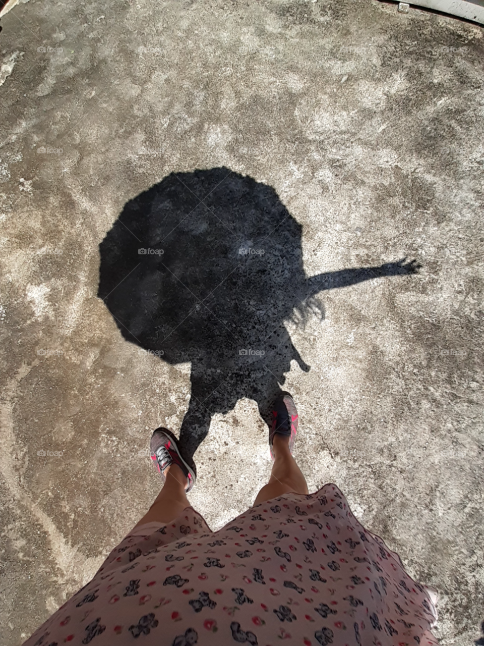 The shadow of an umbrella and the woman holding it under the bright sun of summer.