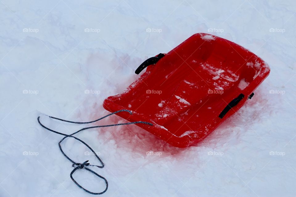 A red plastic snow sled toboggan on the snow in  the mountain