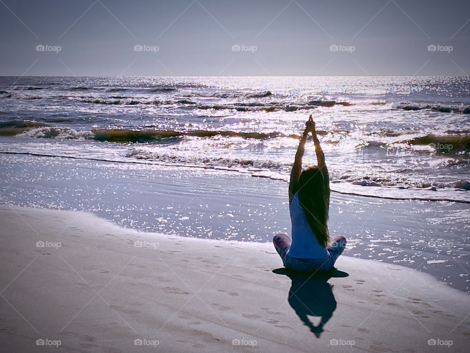 A woman practices yoga on the waters edge at sunrise in Hilton Head, North Carolina