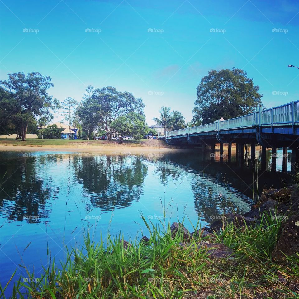Reflections on the river under the blue bridge under blue skies 
