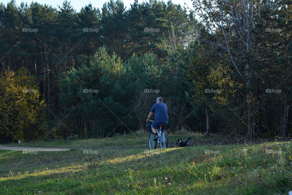 men with dog pet riding on a bike autumn landscape no car day