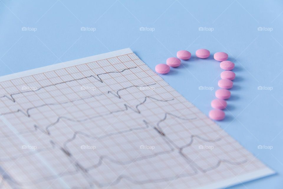 Pills and medicines lie on a blue background with an electrocardiogram of the heart.