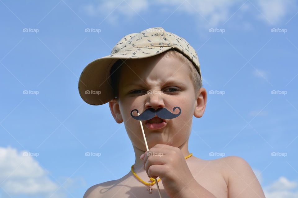 child boy with mustache funny portrait, indulge, outdoor, blue sky background, summer time