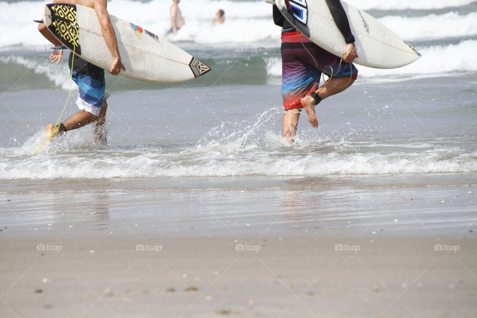 surfers running into the water