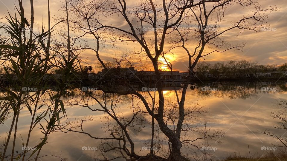 Heading Into Evening High Clouds Partly Separated parting letting in blue sky. Sun glowing with Reflections in water of Lake. Thin Yellow circle around Sun glowing while feathered clouds of Sun. Good clear picture with plenty of detail