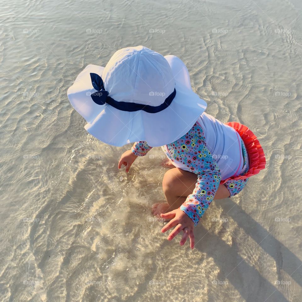 Baby Picking up Shells in the Water on the Emerald Coast in the Gulf of Mexico