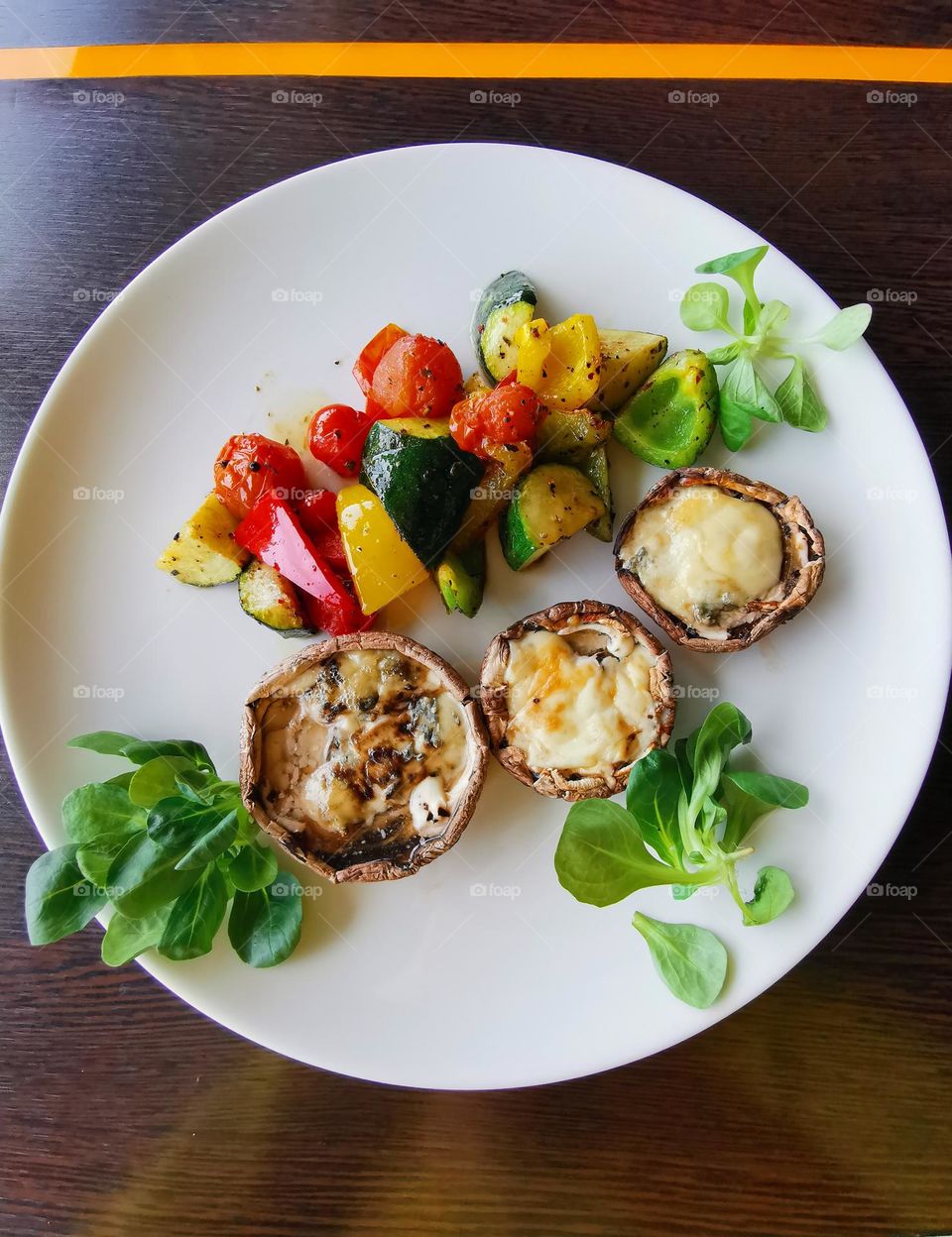 Very tasty and healthy food. Portobello mushrooms, cheese, cherry tomatoes, red, yellow, green pepper and zucchini. Food flatlay.
