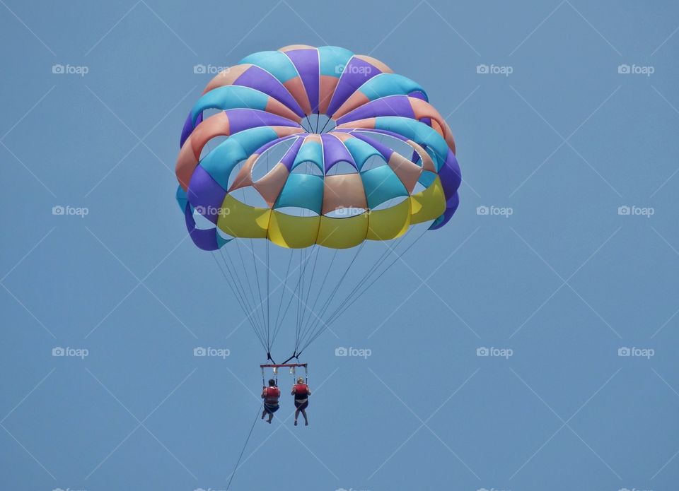 Parasailing. Couple Parasailing Beneath A Colorful Parachute

