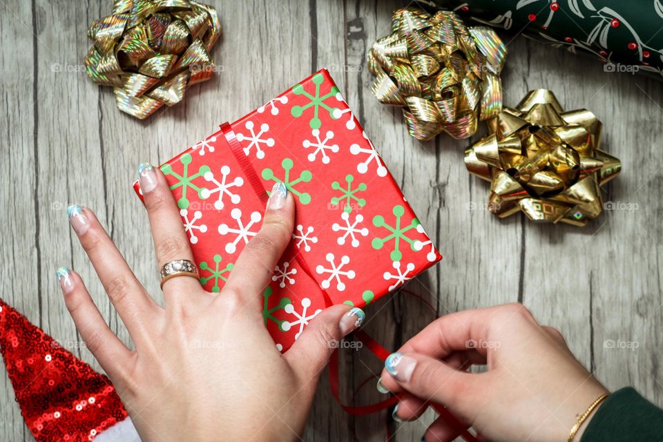 Lady's hands are wrapping a Christmas present