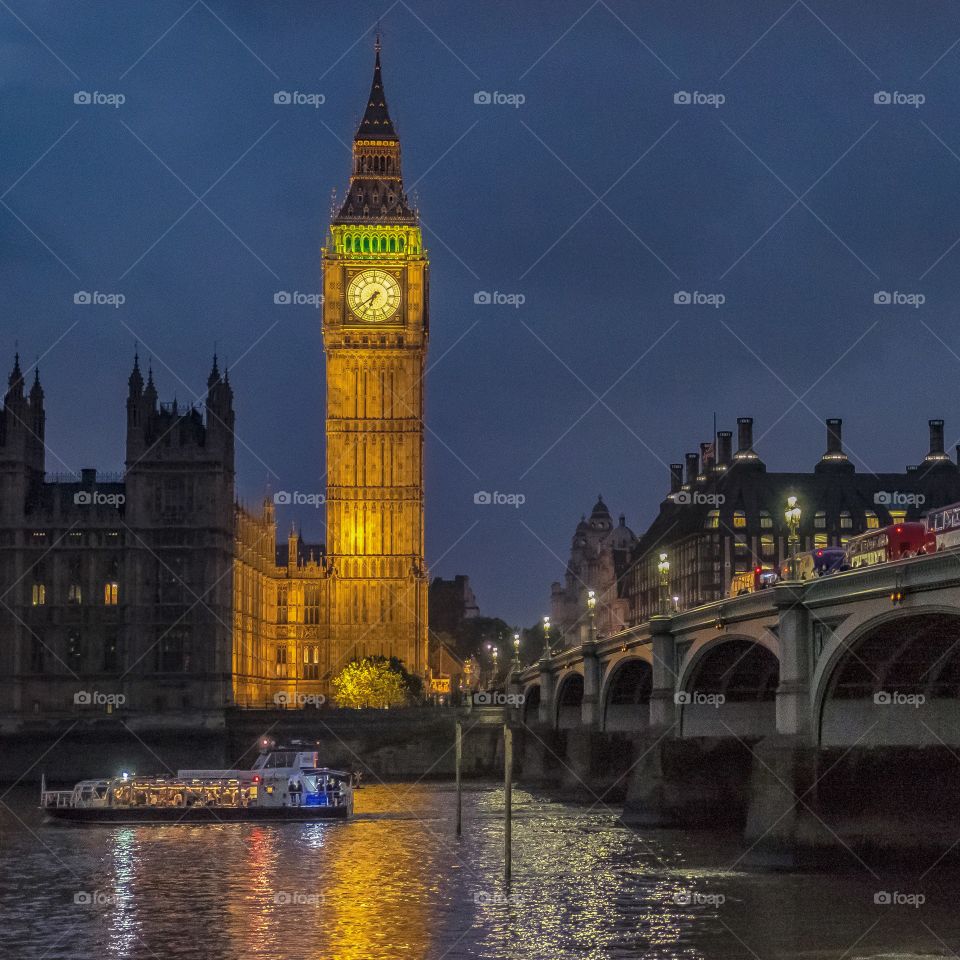 A river boat on London's River Thames approaches Westminster Bridge against the backdrop of London's most famous landmarks, the iconic Elizabeth Tower (commonly known as Big Ben) and the Palace of Westminster.
