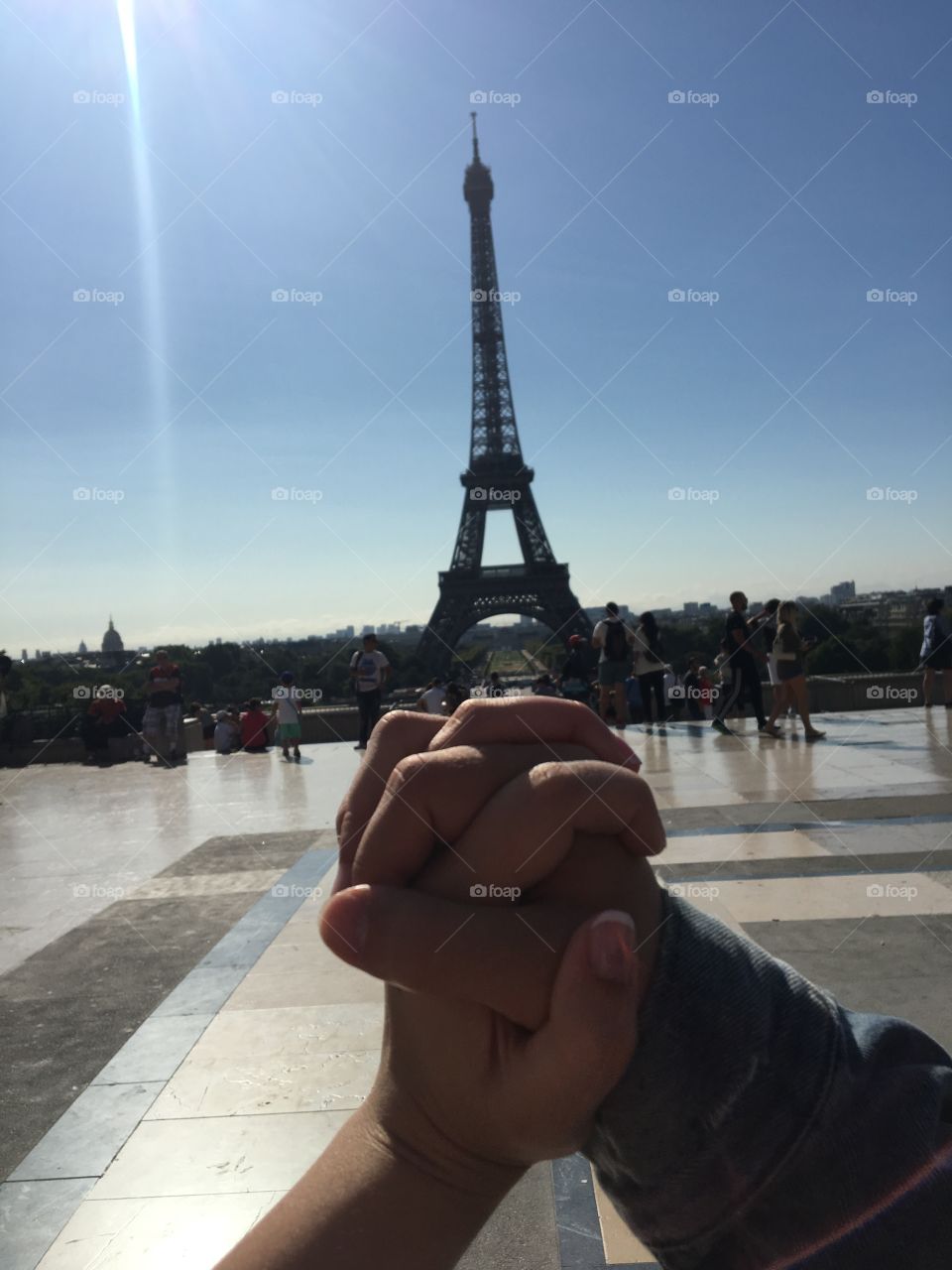 Holding hands in front of the Eiffel Tower in Paris France. 