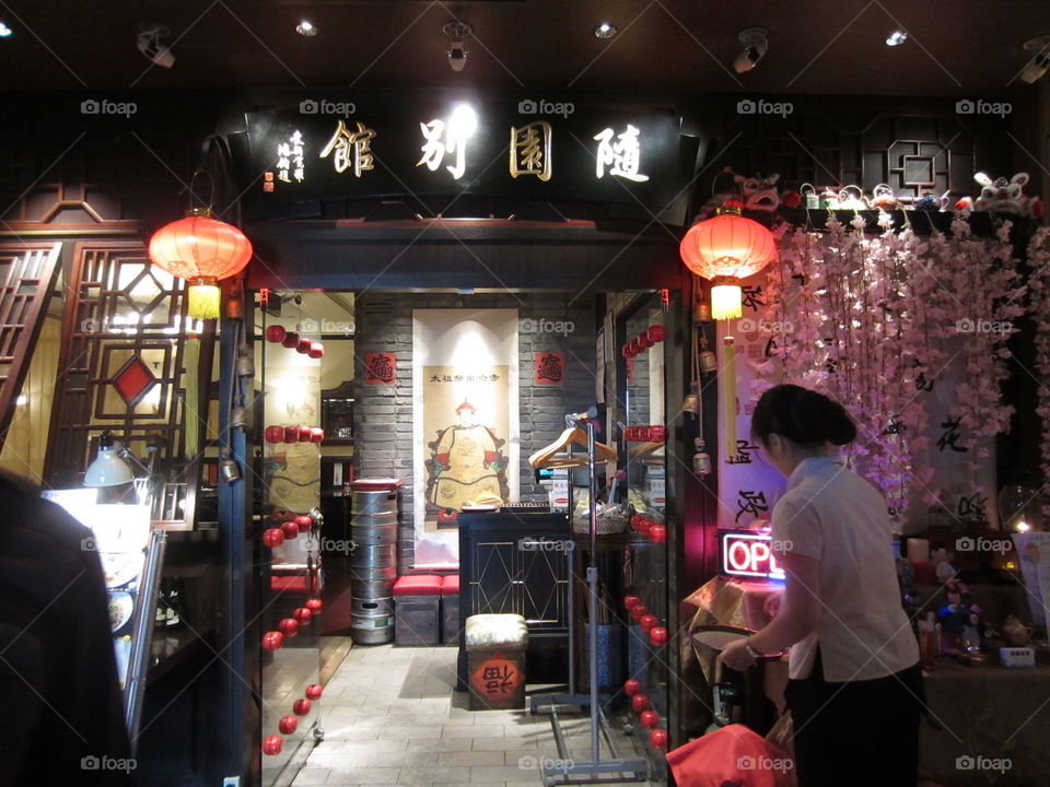 Tokyo Restaurant Entrance with Stained Glass Windows, Paper Lanterns and Dim Lighting, a Woman is Walking In Next to an OPEN Sign