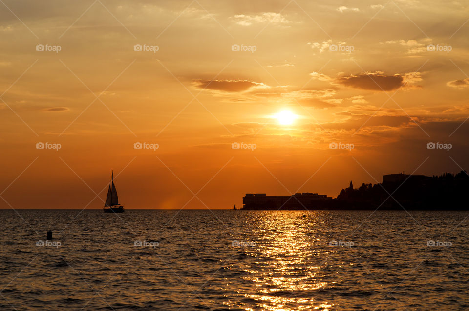 Seaside resort town in Slovenian coast against orange sunset sky in summer. Scenic view of the Adriatic sea in evening.