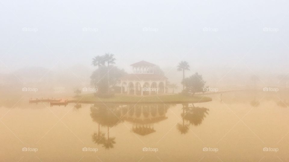 As the sun rises the early morning fog surrounds the gazebo. The beauty of the moment is captured in the reflective water. 