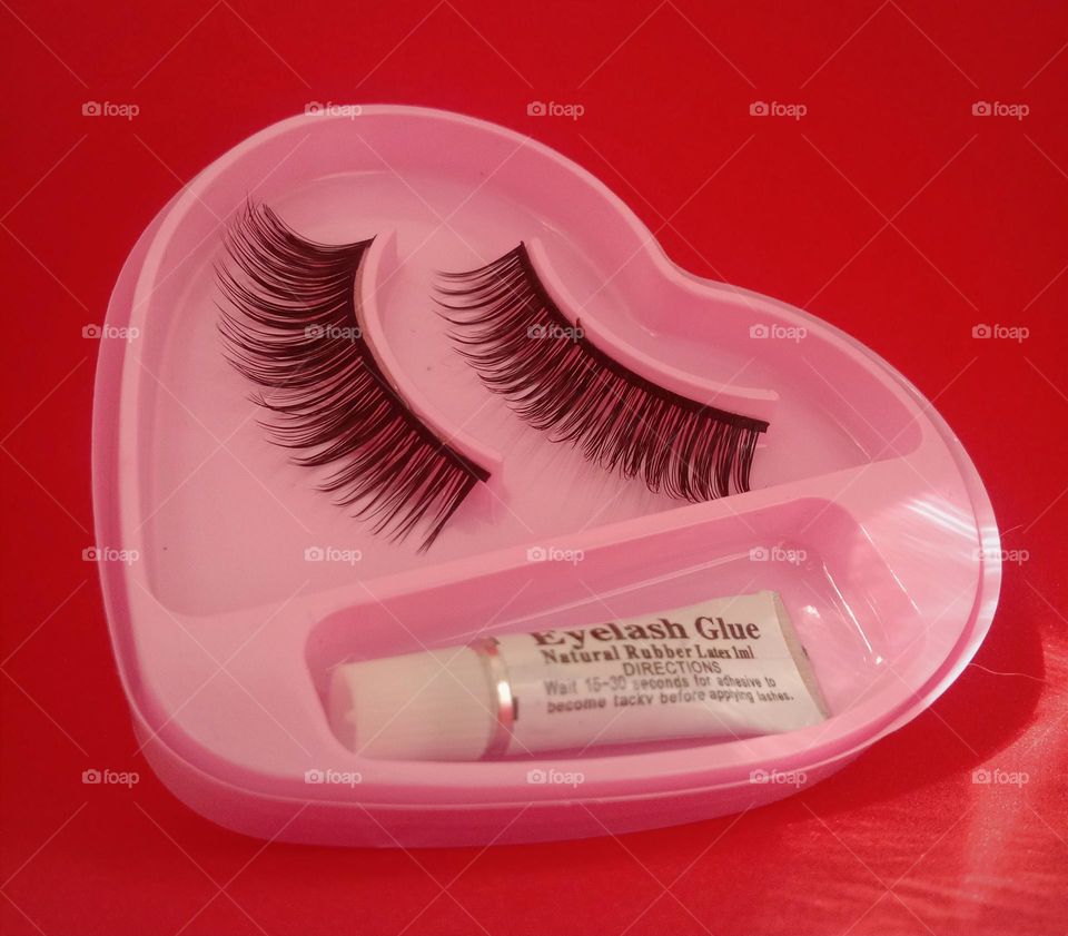 Eyelashes and glue in against red background