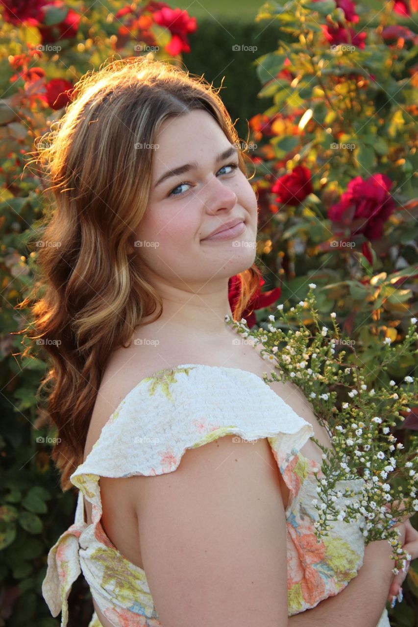 Young lady portrait with roses in background 