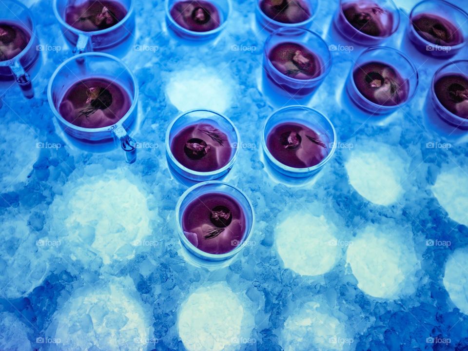 Close-up view of strawberry jelly dessert in a glass cup arranged in cold iced tray