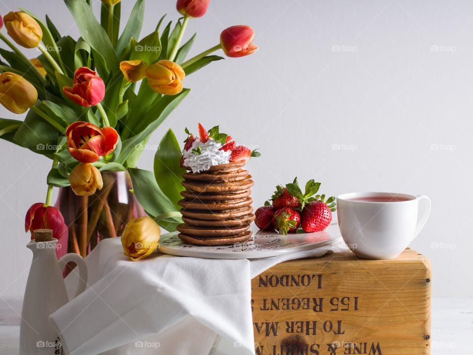 Pancakes with strawberries and colourful spring flowers 