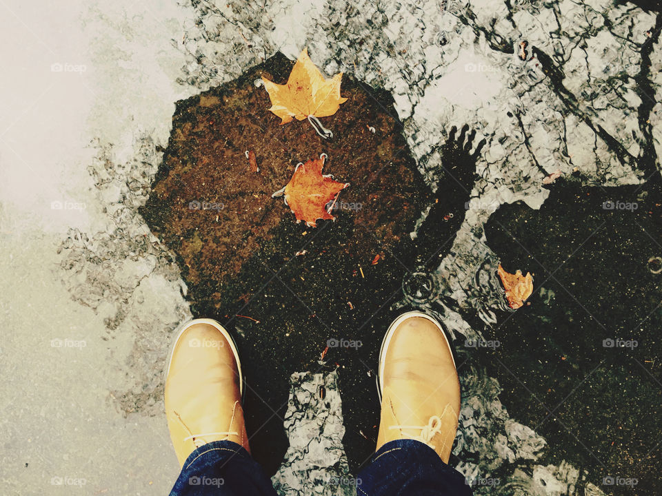 Reflection of a person holding umbrella in puddle