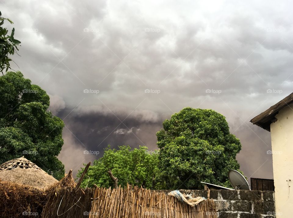 Strong, powerful rain storm and clouds roll in over small, quiet West African rural farming village. 