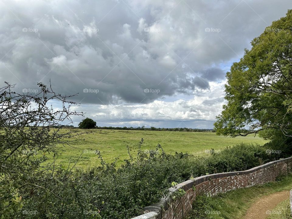 Walking along Oxford canal towpath in Braunston back to narrowboat to continue cruise before weather turns and beautiful sunny clouds rain starts lovely English country field farm scenery