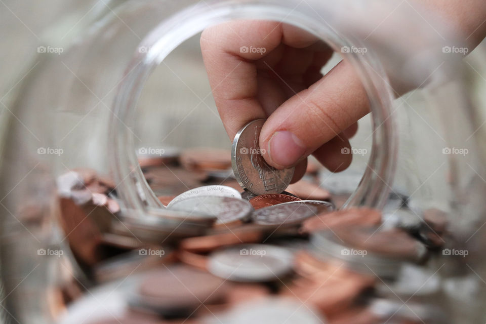 View through the round opening of a glass jar, child holding a coin