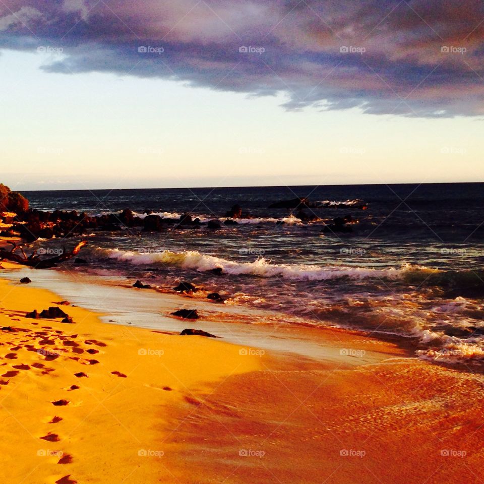 Footprints in sand during sunset