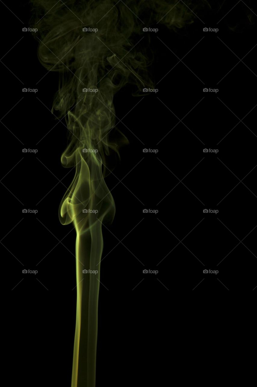 Yellow abstract smoke swirling on black background